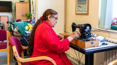 An older woman working on a sewing machine